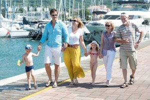 Three generations of a family on  holiday walking along the dock of a luxury marina.